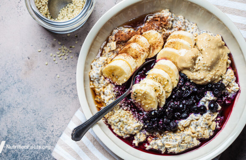 bowl of oatmeal topped with seeds, banana, blueberries, and nut butter