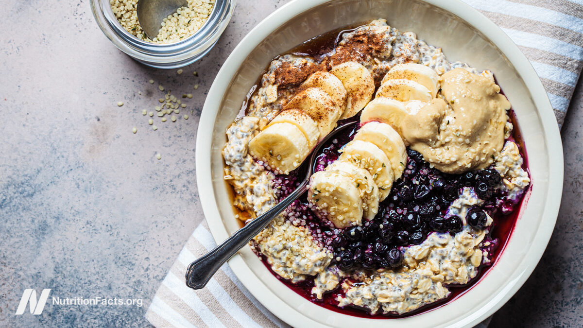 bowl of oatmeal topped with seeds, banana, blueberries, and nut butter